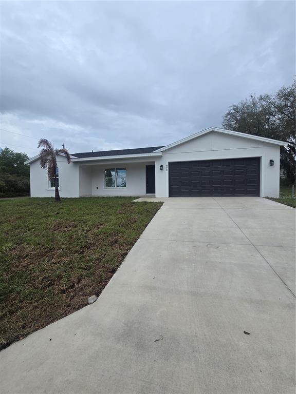 A single-story white house features a dark garage door, a concrete driveway, and a palm tree — 895 S CEDAR AVENUE, ORANGE CITY, FL