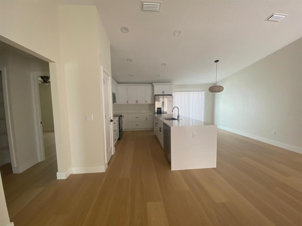 A modern kitchen features white cabinetry, a central island, and light wood flooring — 895 S CEDAR AVENUE, ORANGE CITY, FL