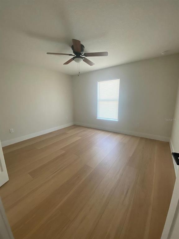 An empty bedroom features light-colored wood flooring, a ceiling fan, and a single window — 895 S CEDAR AVENUE, ORANGE CITY, FL