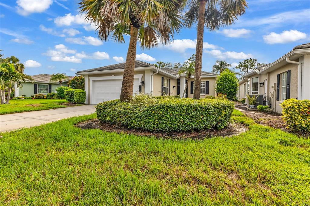 A suburban house with a two-car garage, palm trees, and a manicured front lawn — 834 MONTROSE DRIVE UNIT 9, VENICE, FL