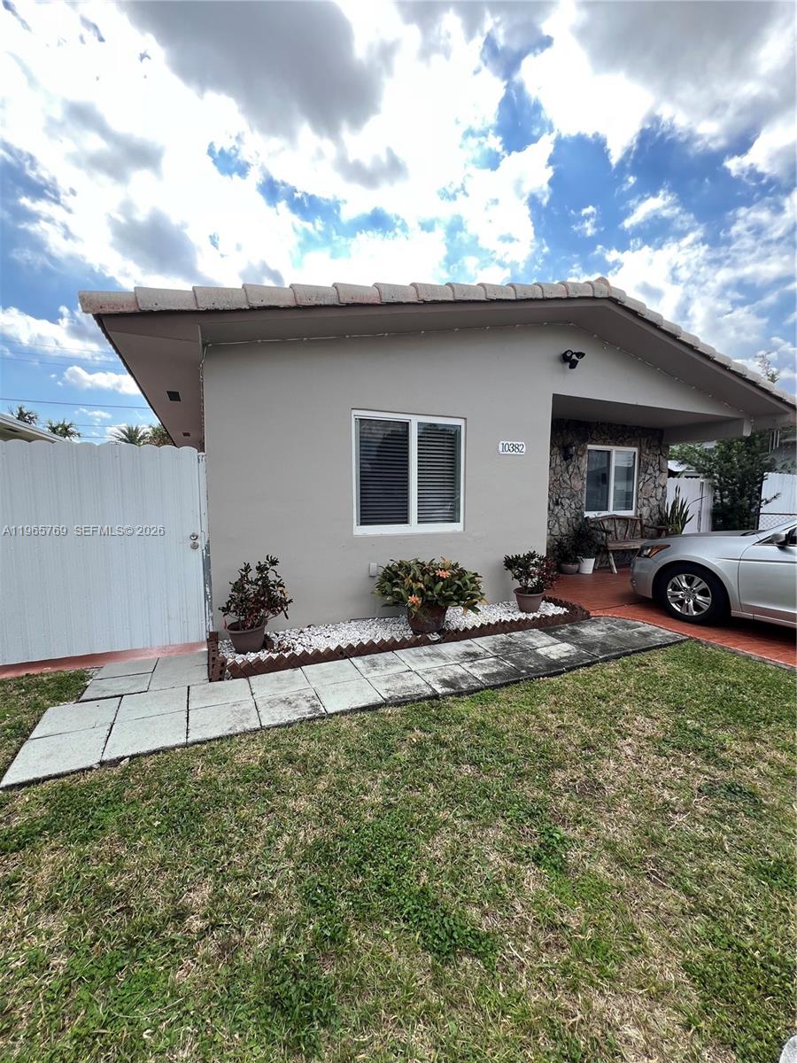 The exterior of a one-story house features a light-colored facade, a stone-accented porch, and landscaping — 10382 SW 25th St, Miami FL 33165, MIAMI, FL