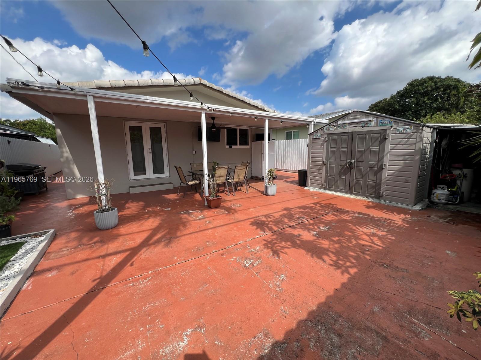 A patio with a covered seating area, a storage shed, and a red concrete floor — 10382 SW 25th St, Miami FL 33165, MIAMI, FL