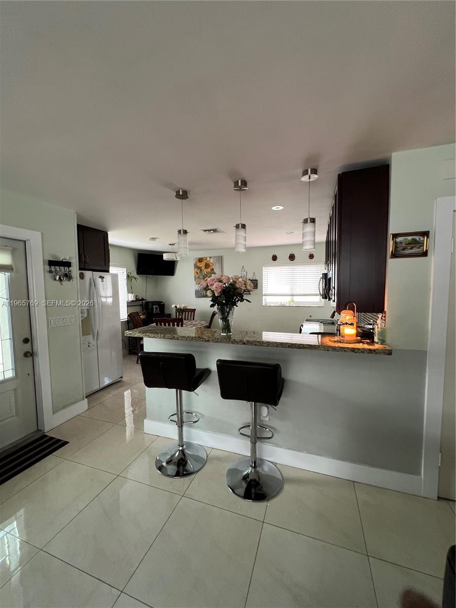 A kitchen features a granite breakfast bar with two stools and dark wood cabinetry — 10382 SW 25th St, Miami FL 33165, MIAMI, FL