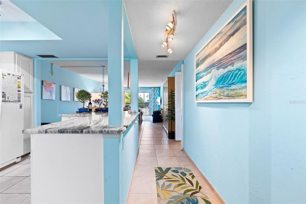 A hallway with light blue walls leads past a kitchen counter toward a living area — 5600 BEACH WAY DRIVE UNIT 210, SARASOTA, FL