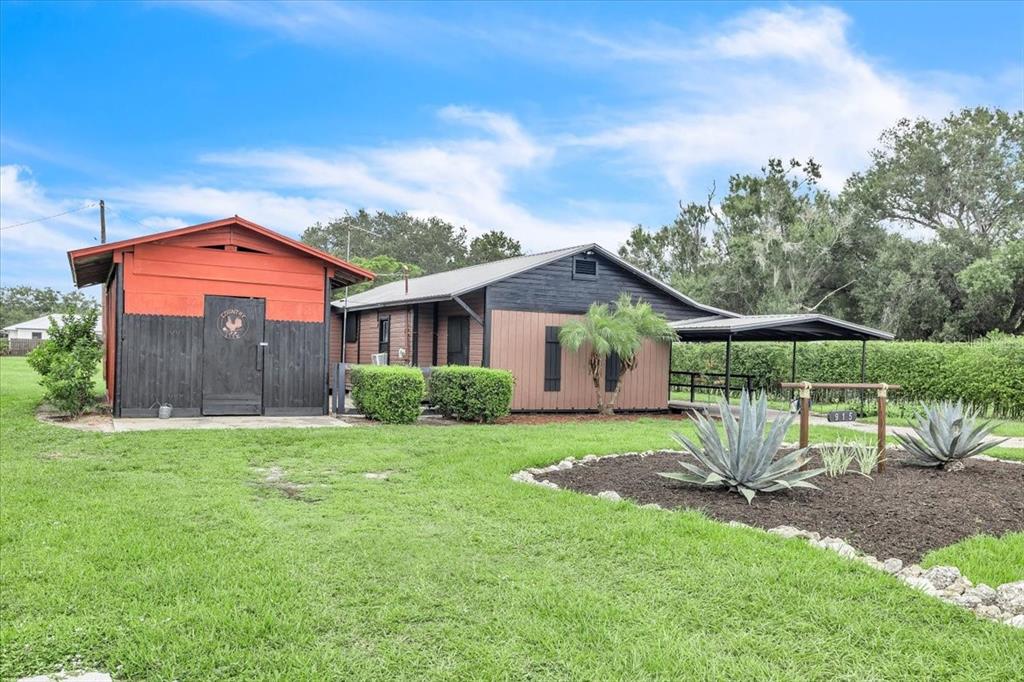 A small house with a red and black exterior, a carport, and a landscaped front yard — 915 E CHARLES STREET, ARCADIA, FL