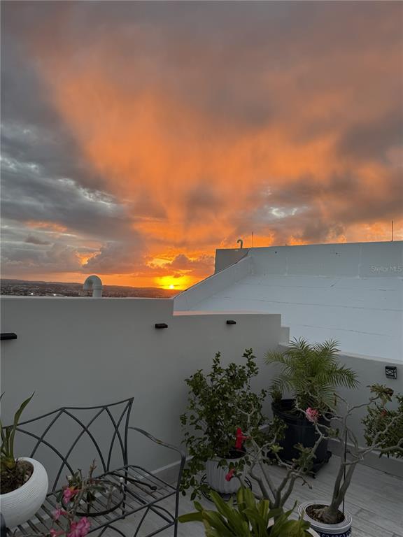 A rooftop terrace features a metal bench, potted plants, and a view of a sunset — Carretera 833 PLAZA DEL PRADO UNIT 1304, GUAYNABO, PR