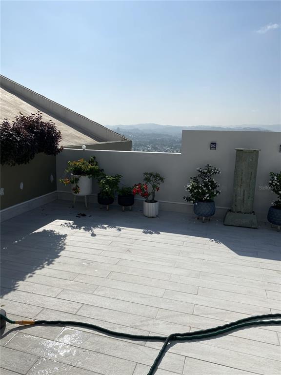 A rooftop terrace features light-colored tile flooring, potted plants, and a view of distant hills — Carretera 833 PLAZA DEL PRADO UNIT 1304, GUAYNABO, PR
