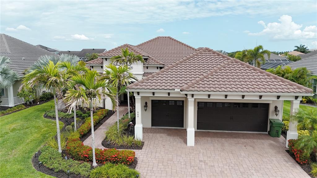 An aerial view of a single-story house with a tiled roof and a paved driveway — 540 REGATTA WAY, BRADENTON, FL