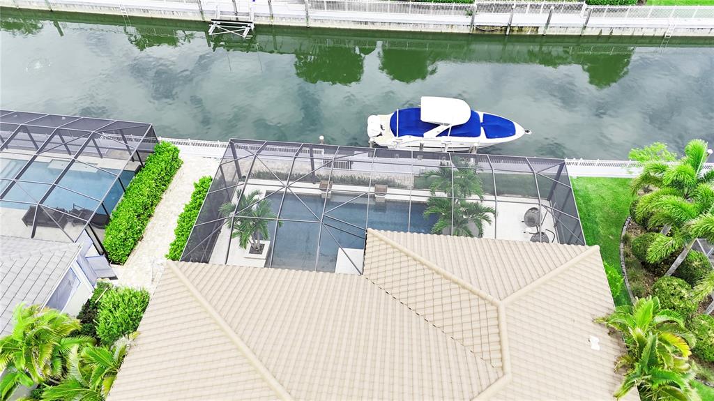 An aerial view shows a house with a screened-in pool and a boat docked nearby — 540 REGATTA WAY, BRADENTON, FL