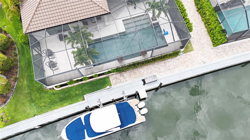 An aerial view shows a house with a screened pool, patio, and a docked boat — 540 REGATTA WAY, BRADENTON, FL