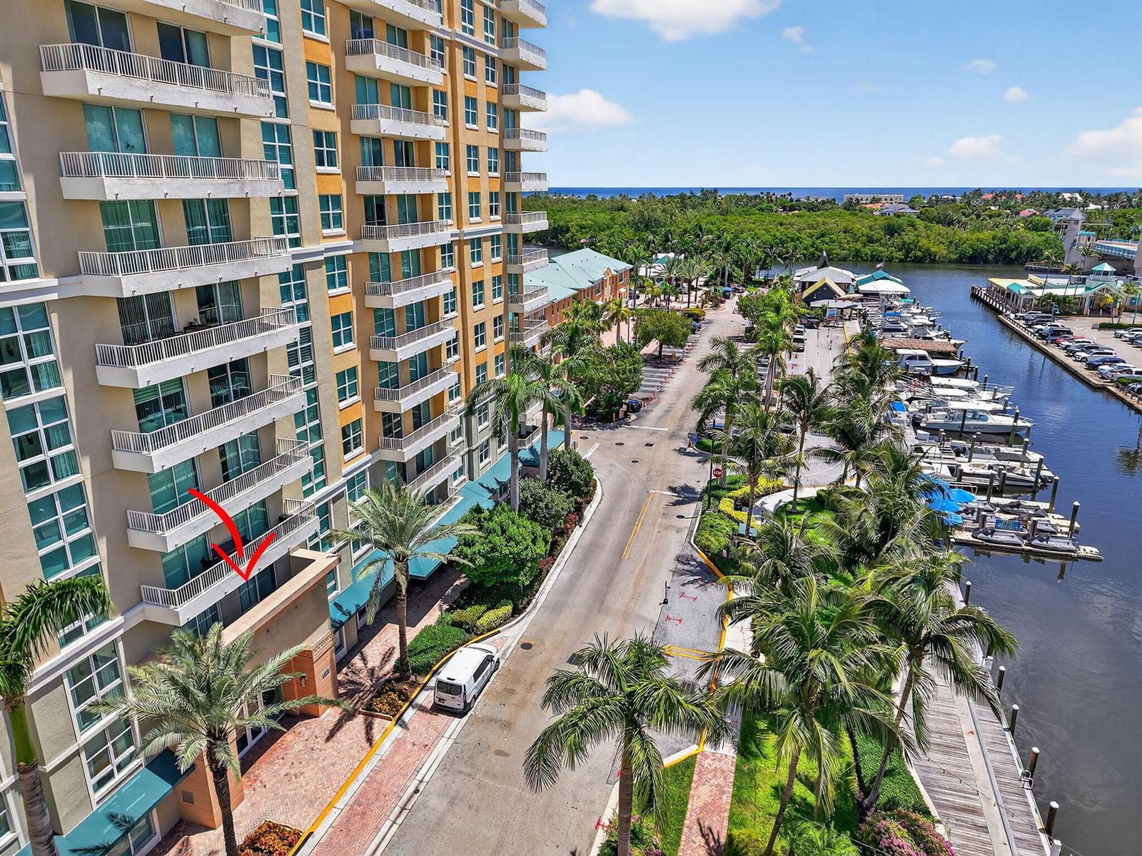 An aerial view shows a high-rise building with balconies overlooking a street and marina — 625 Casa Loma Boulevard # 306, Boynton Beach FL 33435, BOYNTON BEACH, FL