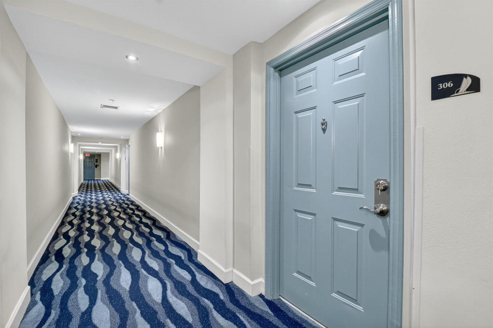 A blue door labeled 306 stands in a hotel hallway with patterned blue carpet — 625 Casa Loma Boulevard # 306, Boynton Beach FL 33435, BOYNTON BEACH, FL