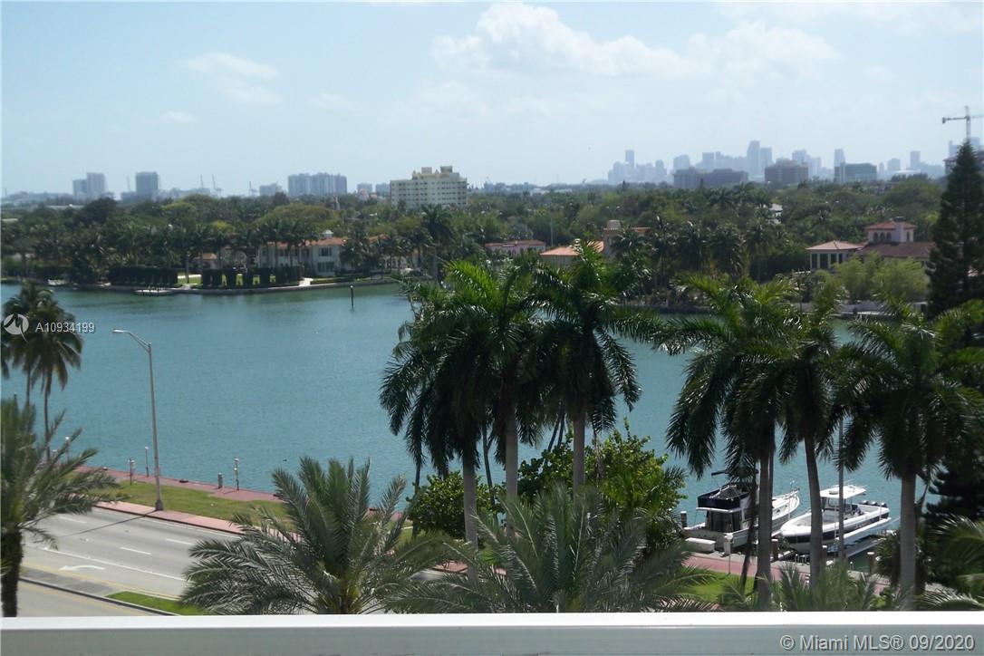An elevated view of a waterway, palm trees, boats, and a distant city skyline — 5161 COLLINS AV # 806, Miami Beach FL 33140, MIAMI BEACH, FL