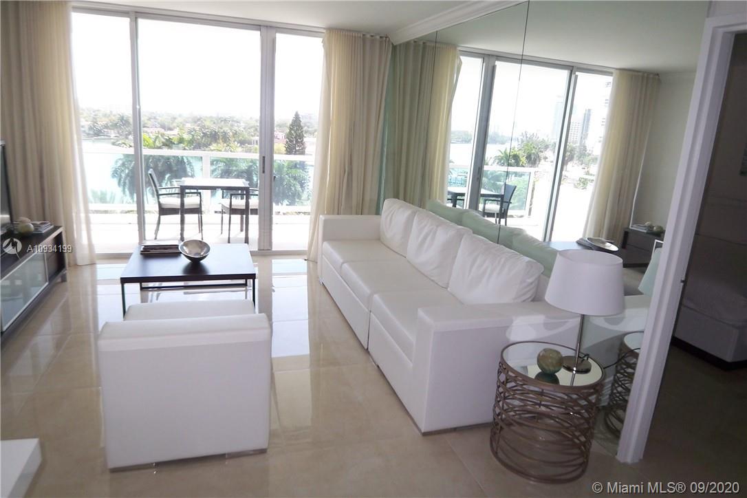 A living room features white leather furniture, tile flooring, and floor-to-ceiling windows overlooking a balcony — 5161 COLLINS AV # 806, Miami Beach FL 33140, MIAMI BEACH, FL