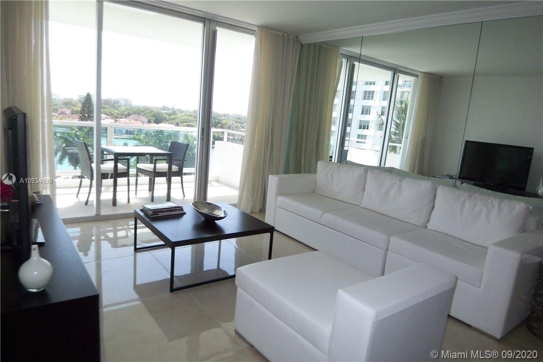 A living room features white furniture, a dark coffee table, and a balcony with water views — 5161 COLLINS AV # 806, Miami Beach FL 33140, MIAMI BEACH, FL