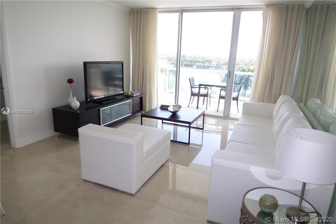 A modern living room features white furniture, a dark media console, and a balcony view — 5161 COLLINS AV # 806, Miami Beach FL 33140, MIAMI BEACH, FL