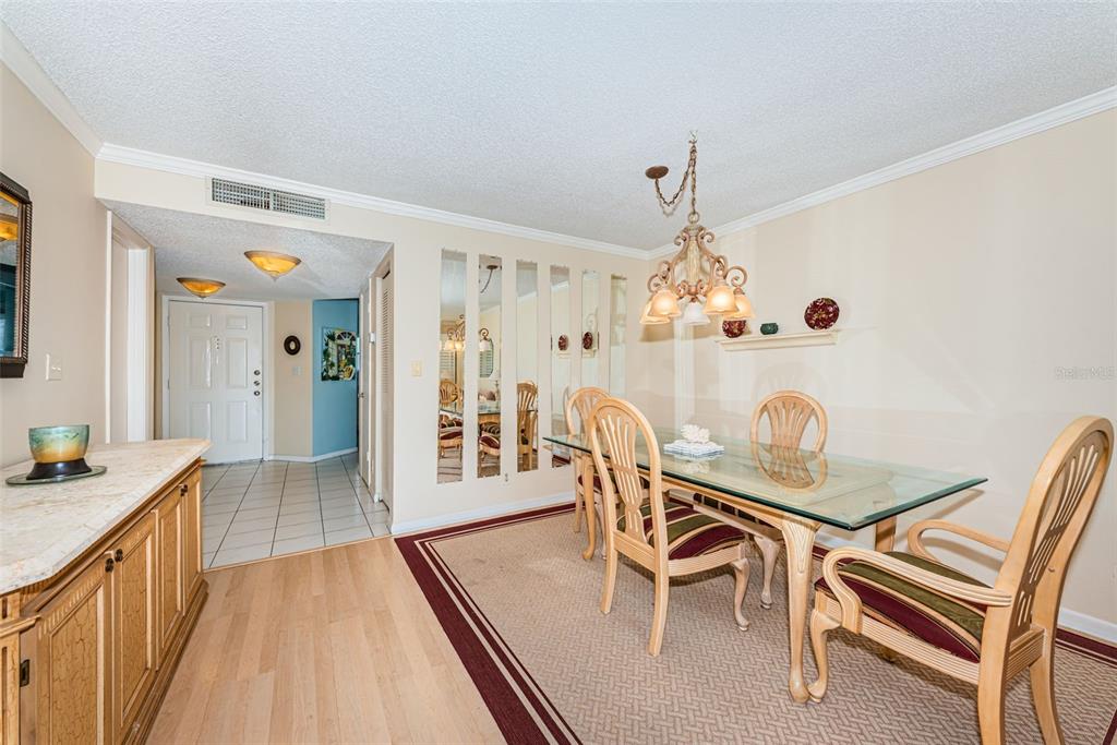A dining room features a glass-top table, wooden chairs, mirrored wall panels, and tile flooring — 6080 BAHIA DEL MAR CIRCLE UNIT 112, ST PETERSBURG, FL