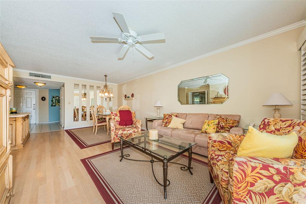 A living room with light wood floors, a beige sofa, and patterned armchairs — 6080 BAHIA DEL MAR CIRCLE UNIT 112, ST PETERSBURG, FL