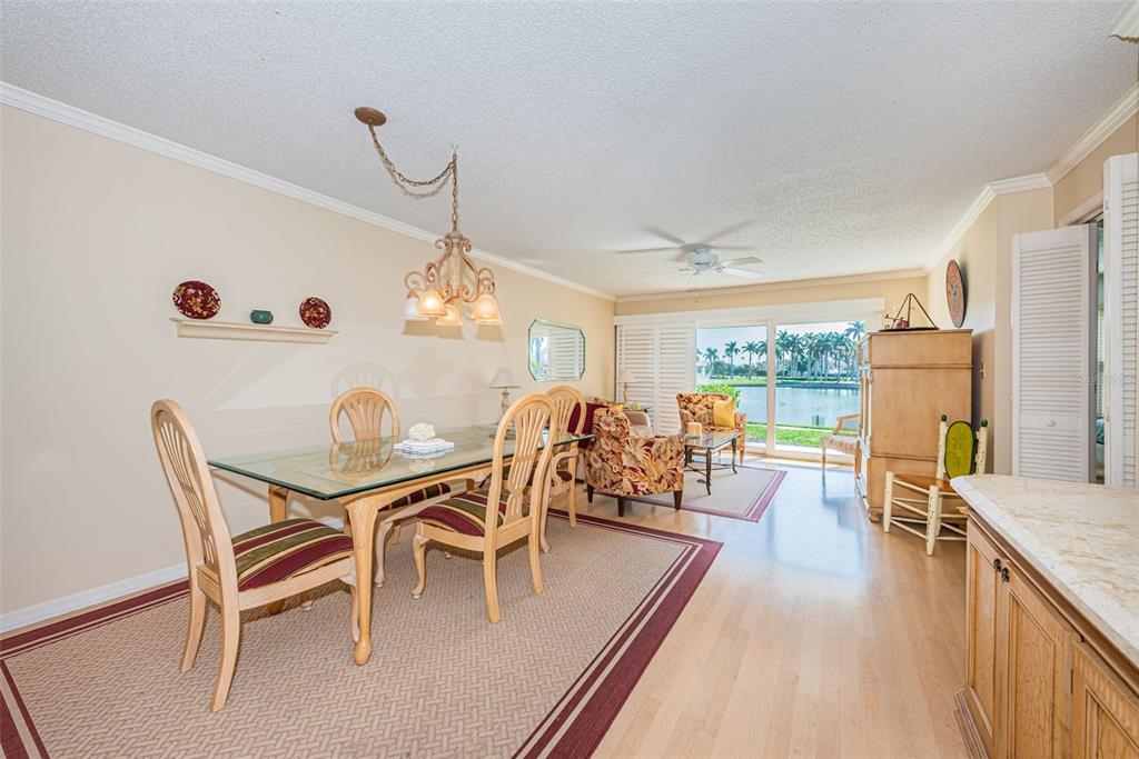 A dining area with a glass table and chairs opens to a living space with water views — 6080 BAHIA DEL MAR CIRCLE UNIT 112, ST PETERSBURG, FL