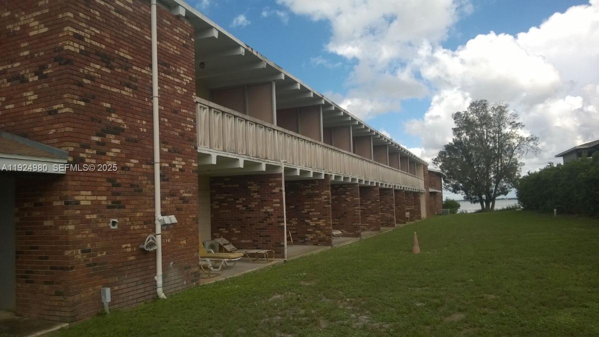 A two-story brick building features a long covered walkway and patio area facing a lawn — 1001 LAKEVIEW DRIVE, Sebring FL 33870, SEBRING, FL