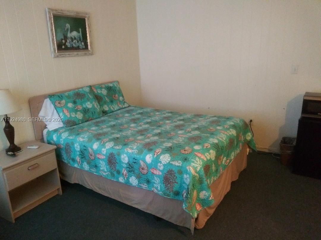 A bedroom features a bed with a teal seashell-patterned quilt and a framed wall picture — 1001 LAKEVIEW DRIVE, Sebring FL 33870, SEBRING, FL