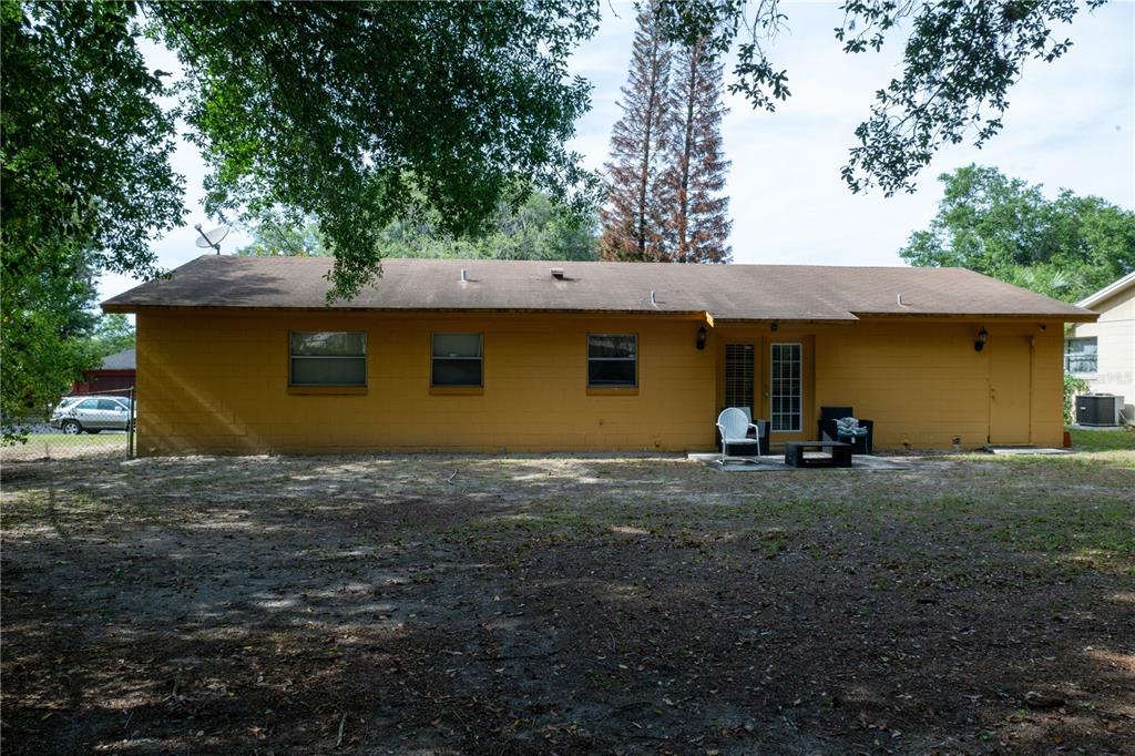 The exterior of a yellow, single-story house with a brown roof and a dirt yard — 6424 SWALLOW HILL DRIVE, ORLANDO, FL