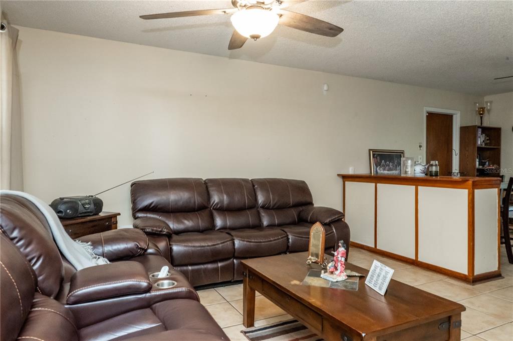 A living room features brown leather sofas, a wooden coffee table, and a built-in bar — 6424 SWALLOW HILL DRIVE, ORLANDO, FL