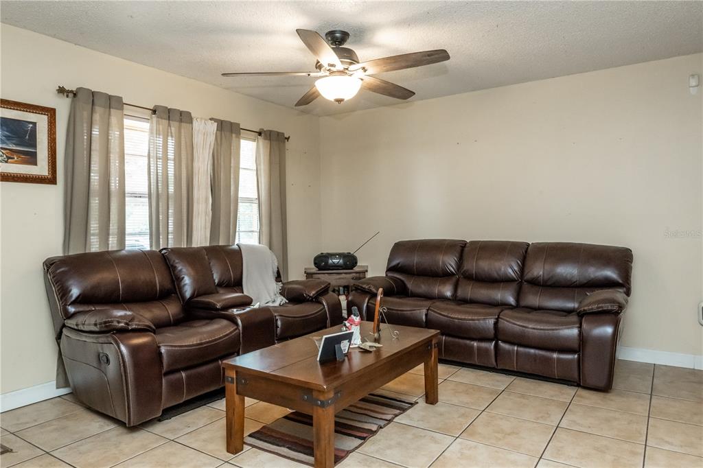 A living room features two brown leather sofas, a wooden coffee table, and tile flooring — 6424 SWALLOW HILL DRIVE, ORLANDO, FL