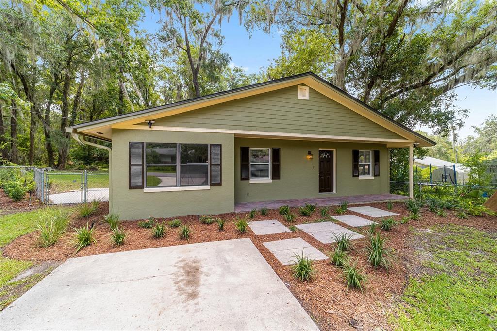 A single-story green house with a concrete walkway and a covered front porch — 755 SE 29TH TERRACE, OCALA, FL