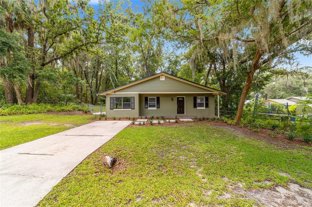 A single-story olive green house with a concrete driveway sits on a grassy lot — 755 SE 29TH TERRACE, OCALA, FL