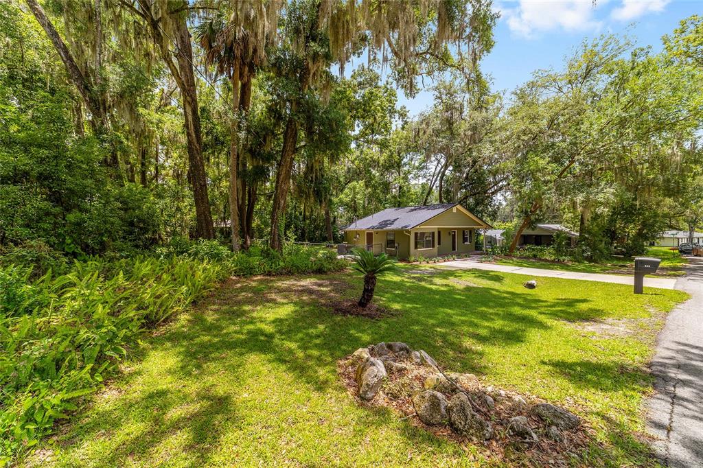 A small, olive-green house sits on a grassy lot surrounded by large, moss-draped trees — 755 SE 29TH TERRACE, OCALA, FL