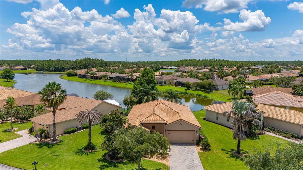 An aerial view shows a suburban house with a tile roof and a backyard lake — 394 MONTEREY STREET, KISSIMMEE, FL