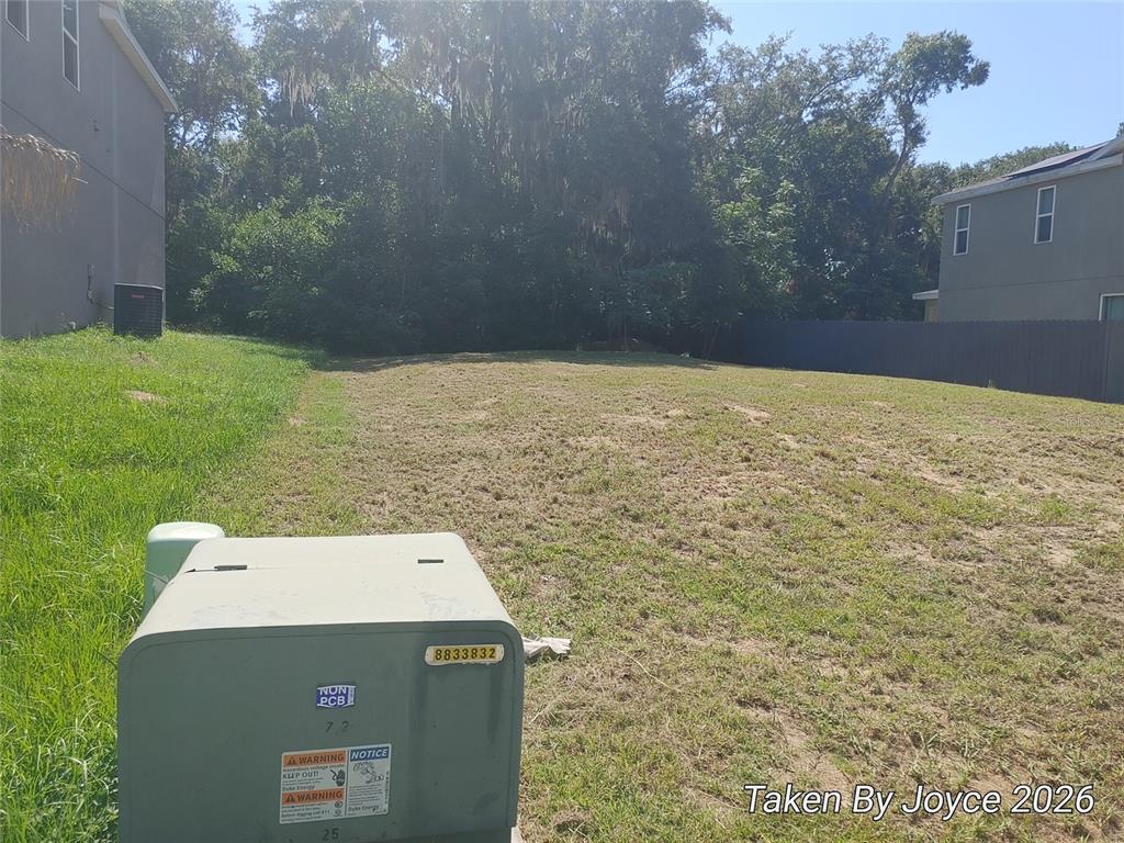 A grassy residential lot sits between two houses with a utility box in the foreground — Lot 14 BELLISSIMO PLACE, HOWEY IN THE HILLS, FL