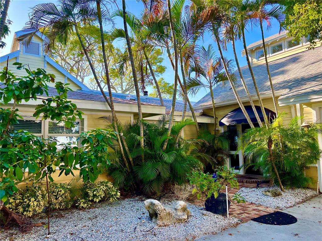A yellow house with a brick walkway, palm trees, and a dark blue awning — 615 N MAYO STREET, CRYSTAL BEACH, FL