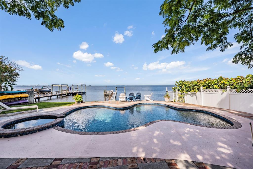 A swimming pool and hot tub overlook a dock on a large body of water — 615 N MAYO STREET, CRYSTAL BEACH, FL