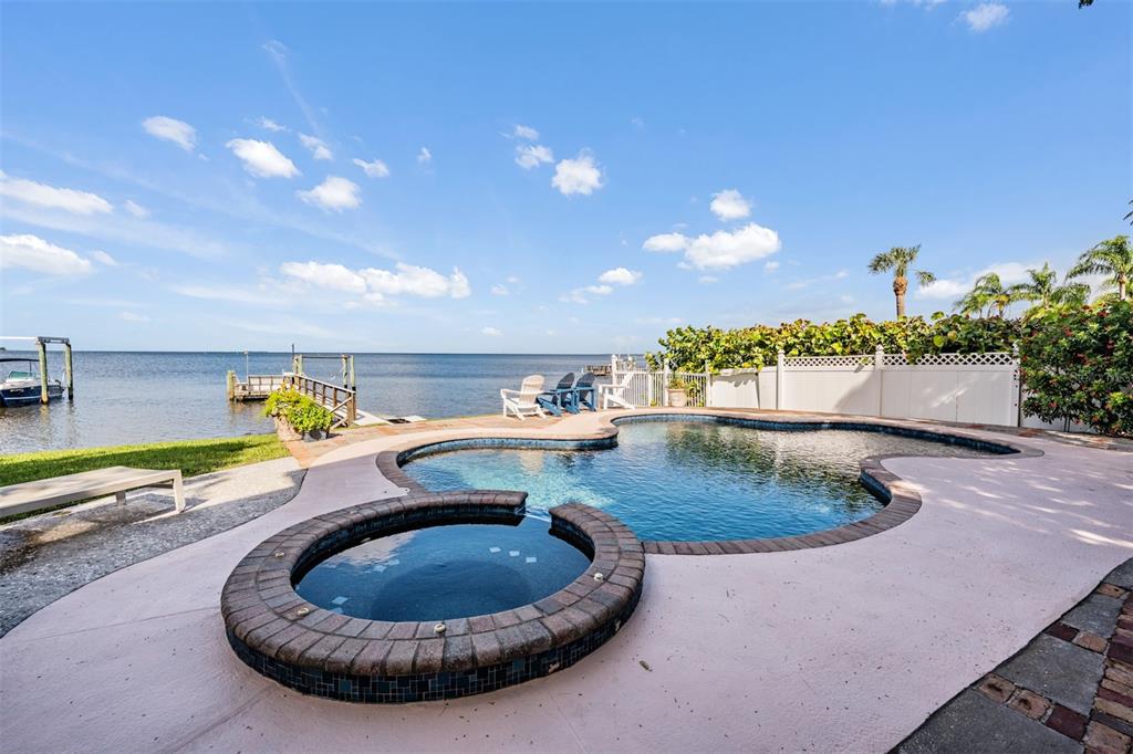 A backyard swimming pool and hot tub overlook a waterfront dock on a sunny day — 615 N MAYO STREET, CRYSTAL BEACH, FL