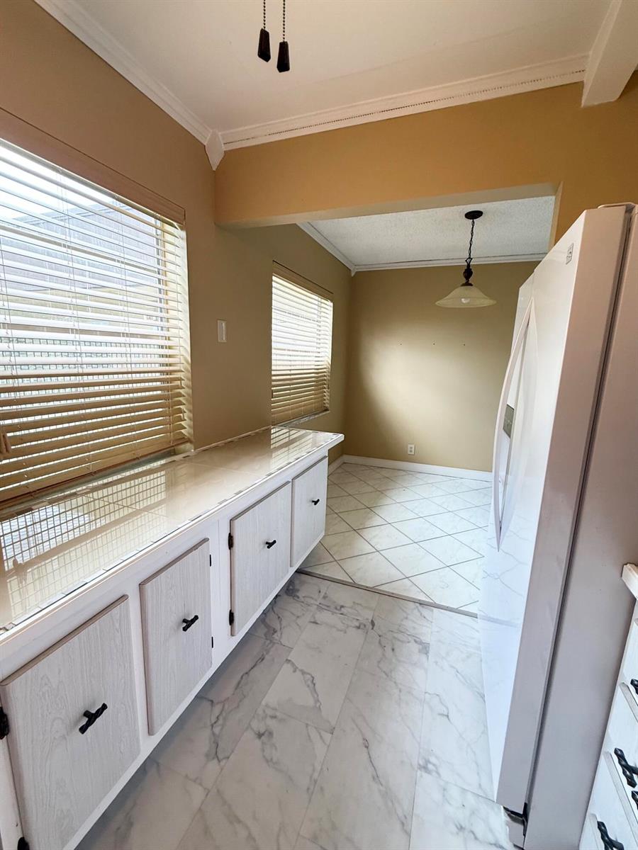 A kitchen area features white cabinets, a tiled countertop, and marble-look flooring — 814 Burgundy Q, Delray Beach FL 33484, DELRAY BEACH, FL