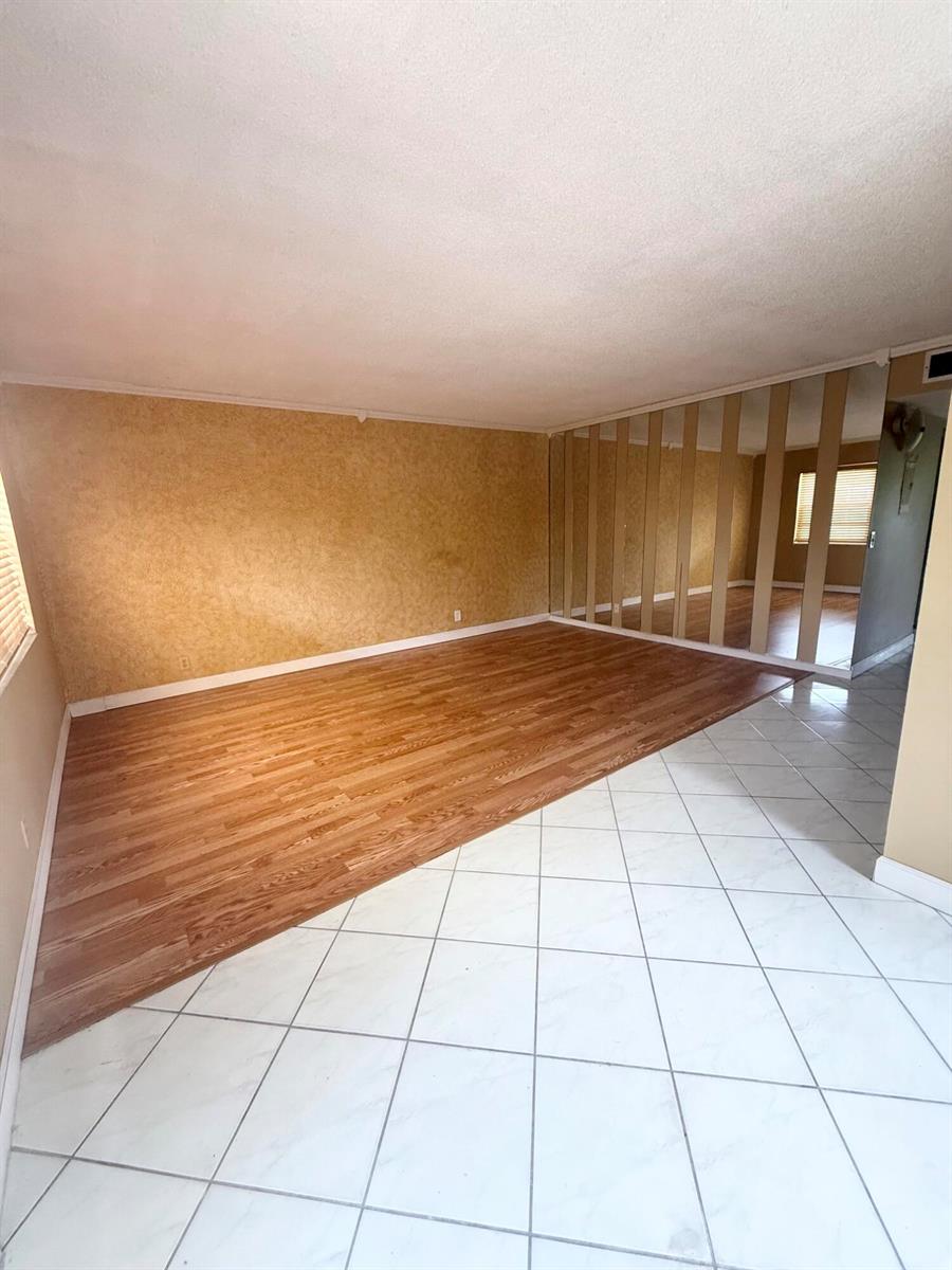 A room features a diagonal transition between wood-look laminate flooring and white tiled flooring — 814 Burgundy Q, Delray Beach FL 33484, DELRAY BEACH, FL