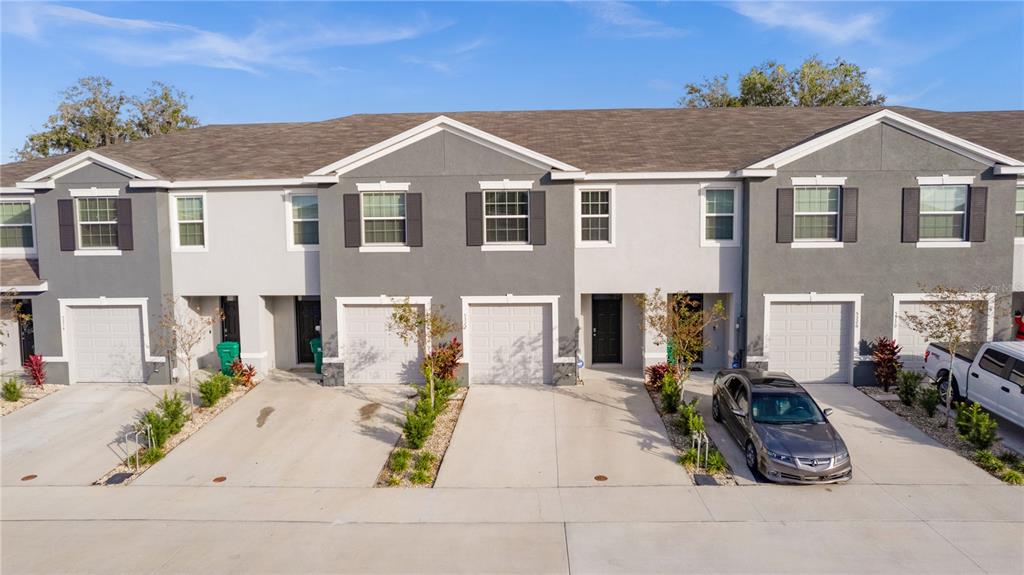 An exterior view of a multi-unit townhouse complex with gray and white stucco facades — 5322 DRAGON FLY DRIVE, WILDWOOD, FL