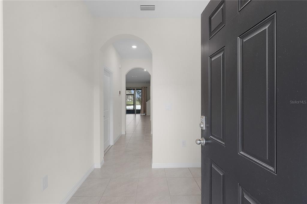 An open front door reveals a tiled entryway leading to a hallway with arched transitions — 5322 DRAGON FLY DRIVE, WILDWOOD, FL