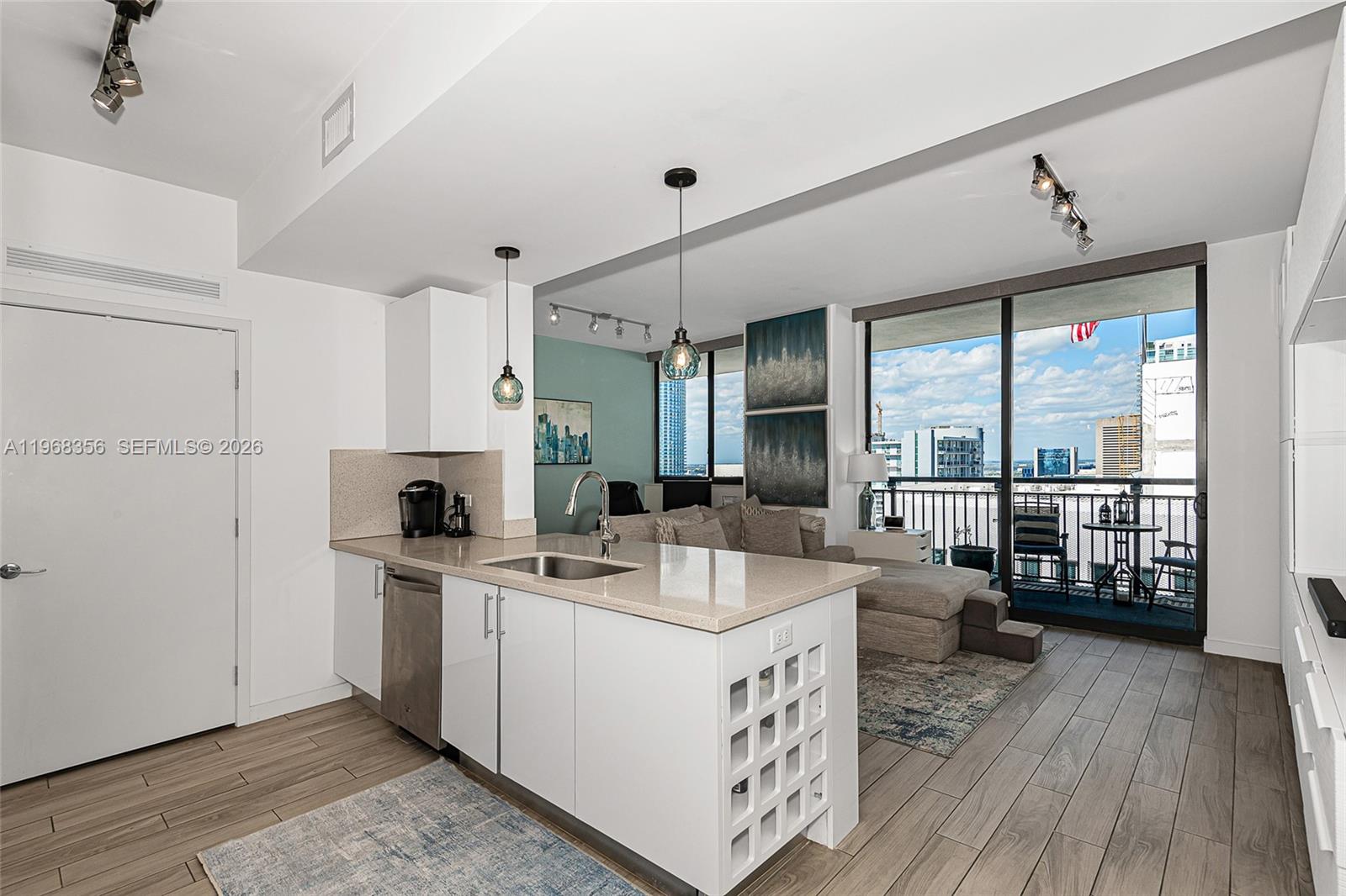 A modern kitchen with white cabinetry and a wine rack island overlooks a living area — 999 SW 1st Ave # 3215, Miami FL 33130, MIAMI, FL