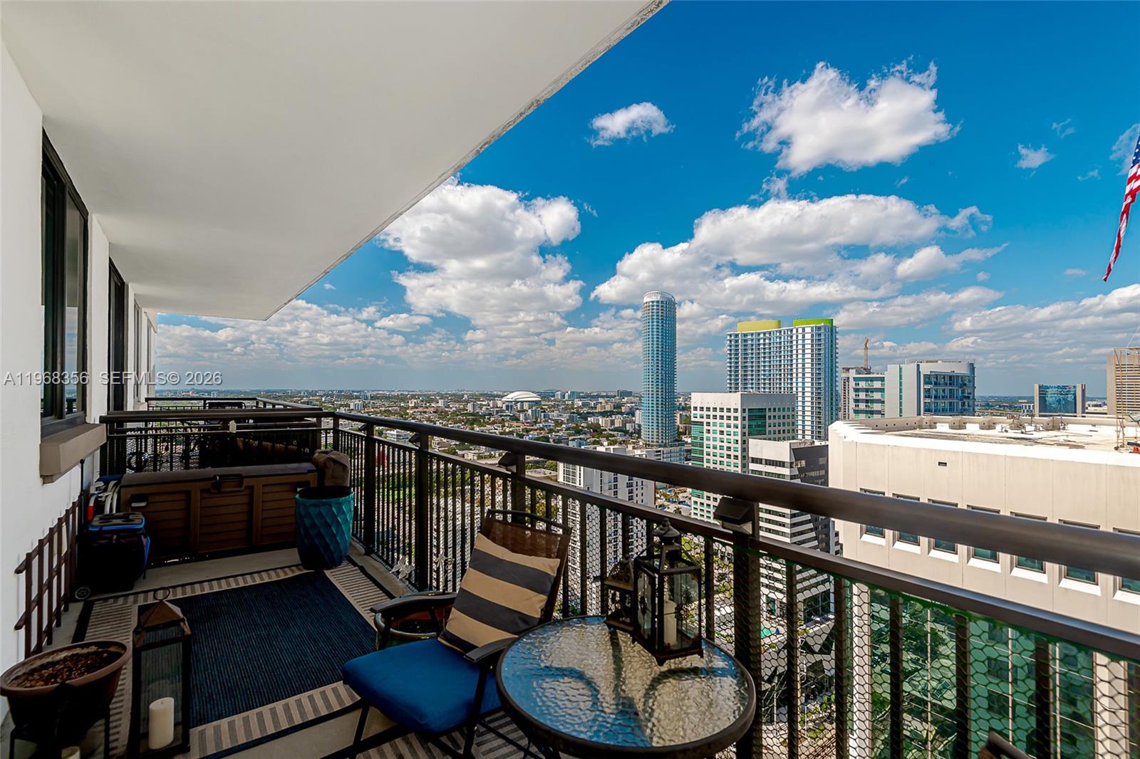 A high-rise balcony features outdoor furniture overlooking a city skyline under a blue sky — 999 SW 1st Ave # 3215, Miami FL 33130, MIAMI, FL