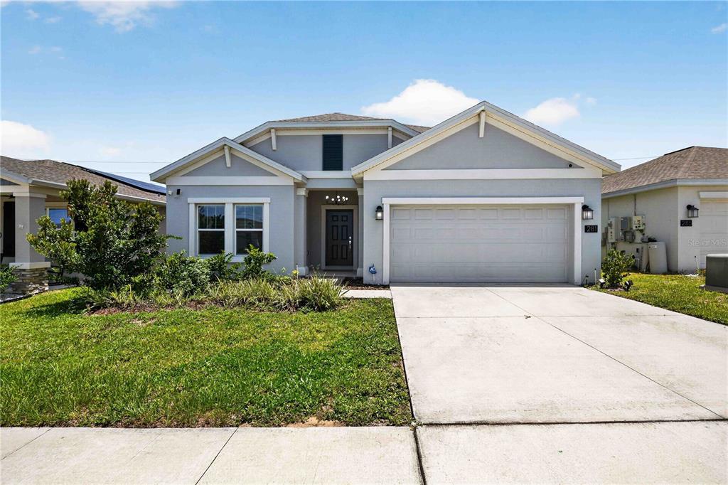 A single-story house with a light gray exterior, a two-car garage, and a front lawn — 281 PIAVE STREET, HAINES CITY, FL