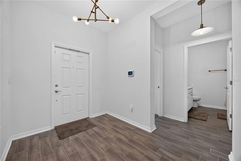 An entryway with wood-look tile flooring, a white front door, and a modern chandelier — 281 PIAVE STREET, HAINES CITY, FL