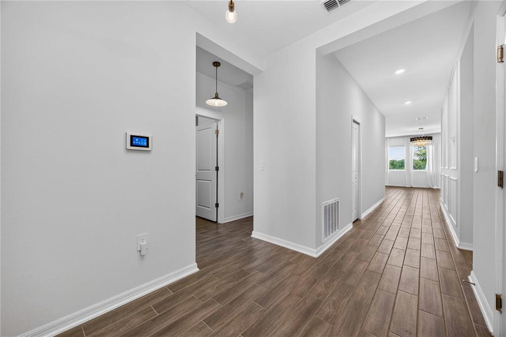 A hallway with wood-look tile flooring leads toward a bright room with large windows — 281 PIAVE STREET, HAINES CITY, FL