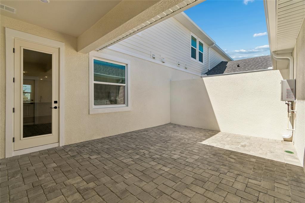 A paved patio area features a glass door, a window, and a privacy wall — 8215 SEAFLOWER PARKWAY, BRADENTON, FL