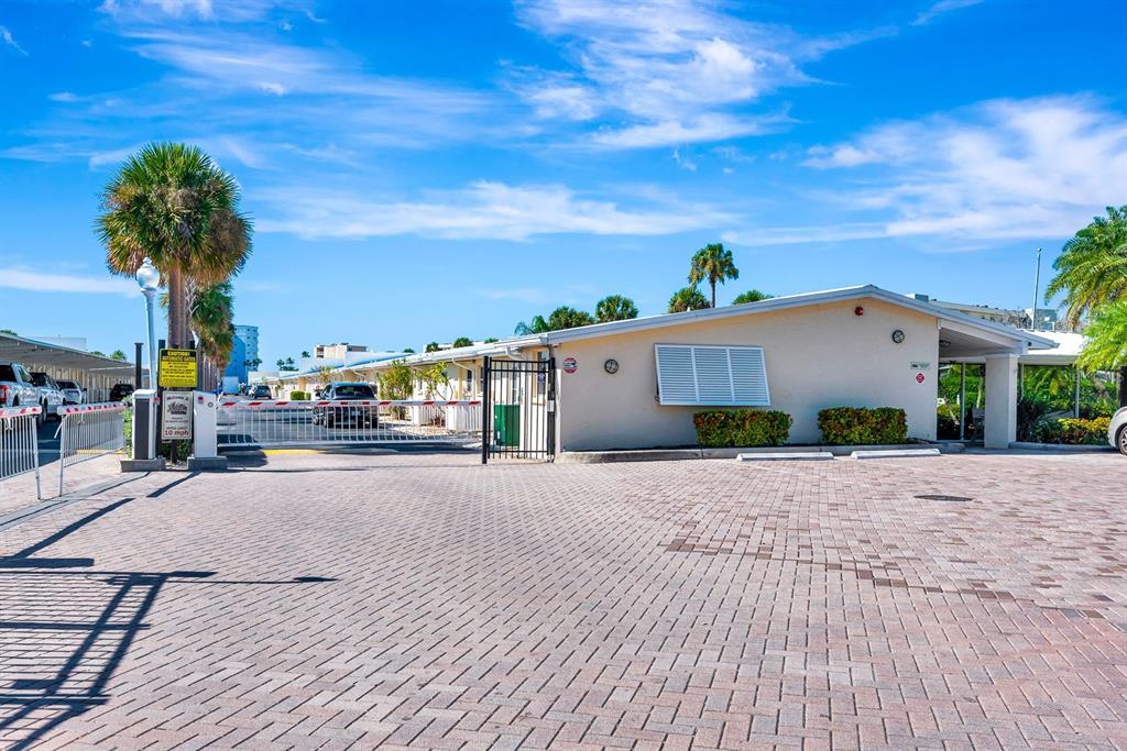A stone-based monument sign for Jamaica Royale stands outdoors surrounded by tropical landscaping — 5830 MIDNIGHT PASS ROAD UNIT 61, SARASOTA, FL