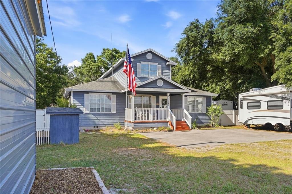 A blue two-story house with a front porch, an American flag, and a parked RV — 10049 QUINN ROAD, POLK CITY, FL