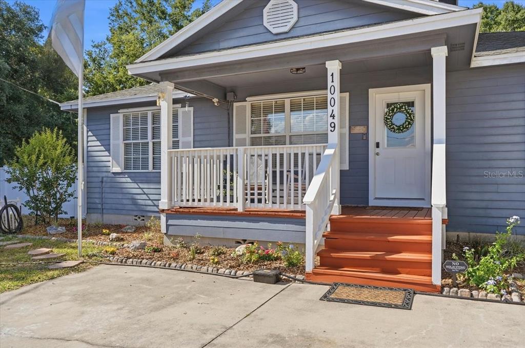 A blue house features a front porch with white railings and wooden steps — 10049 QUINN ROAD, POLK CITY, FL