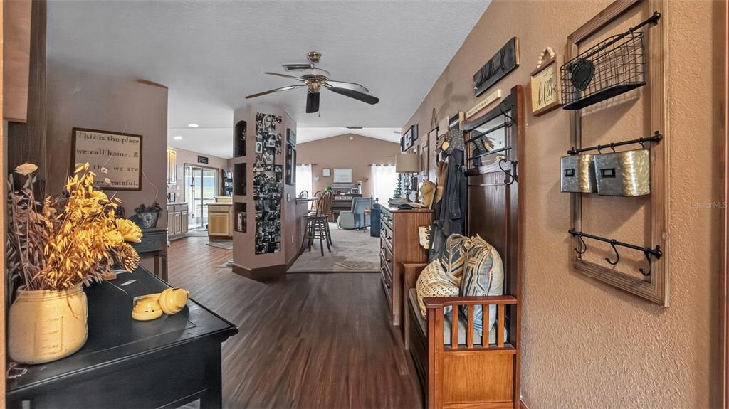 A hallway leads into a living area with wood-look flooring and a ceiling fan — 706 MURRAY CIRCLE, LADY LAKE, FL